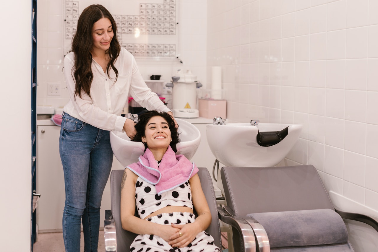 Hairdresser is performing hair treatment to a woman