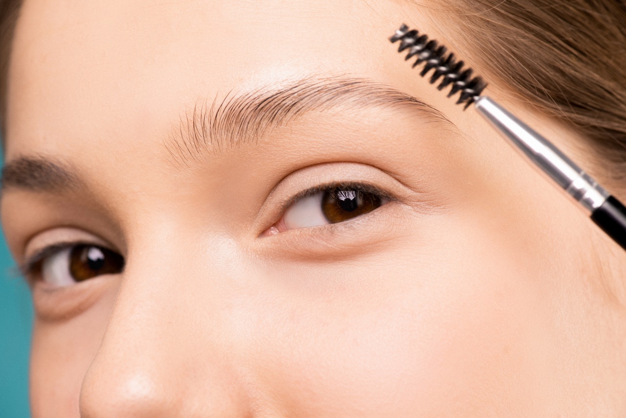 Blonde woman is using eyebrow brush to make her eyebrows look better