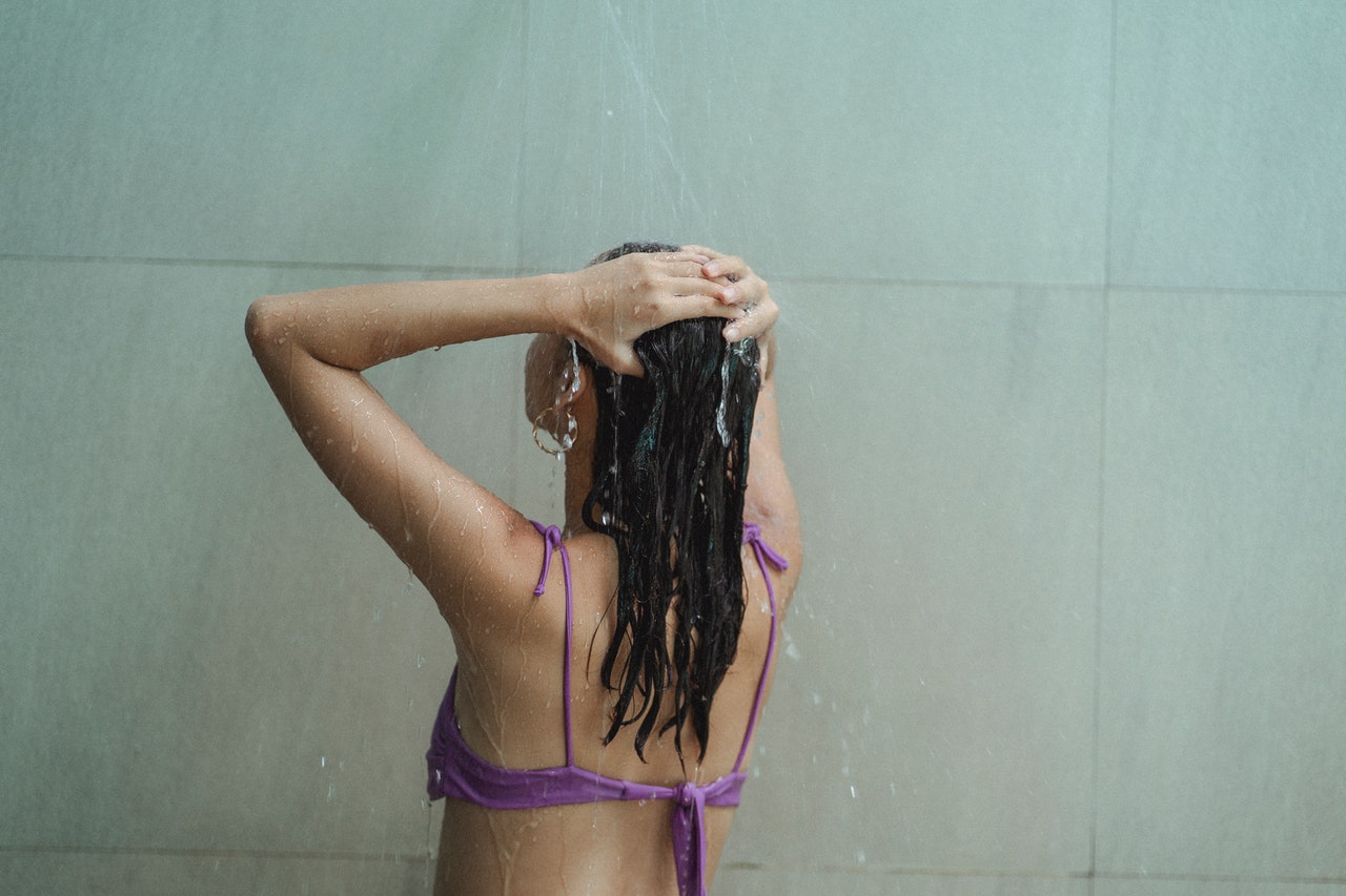 Woman is under the shower washing her hair